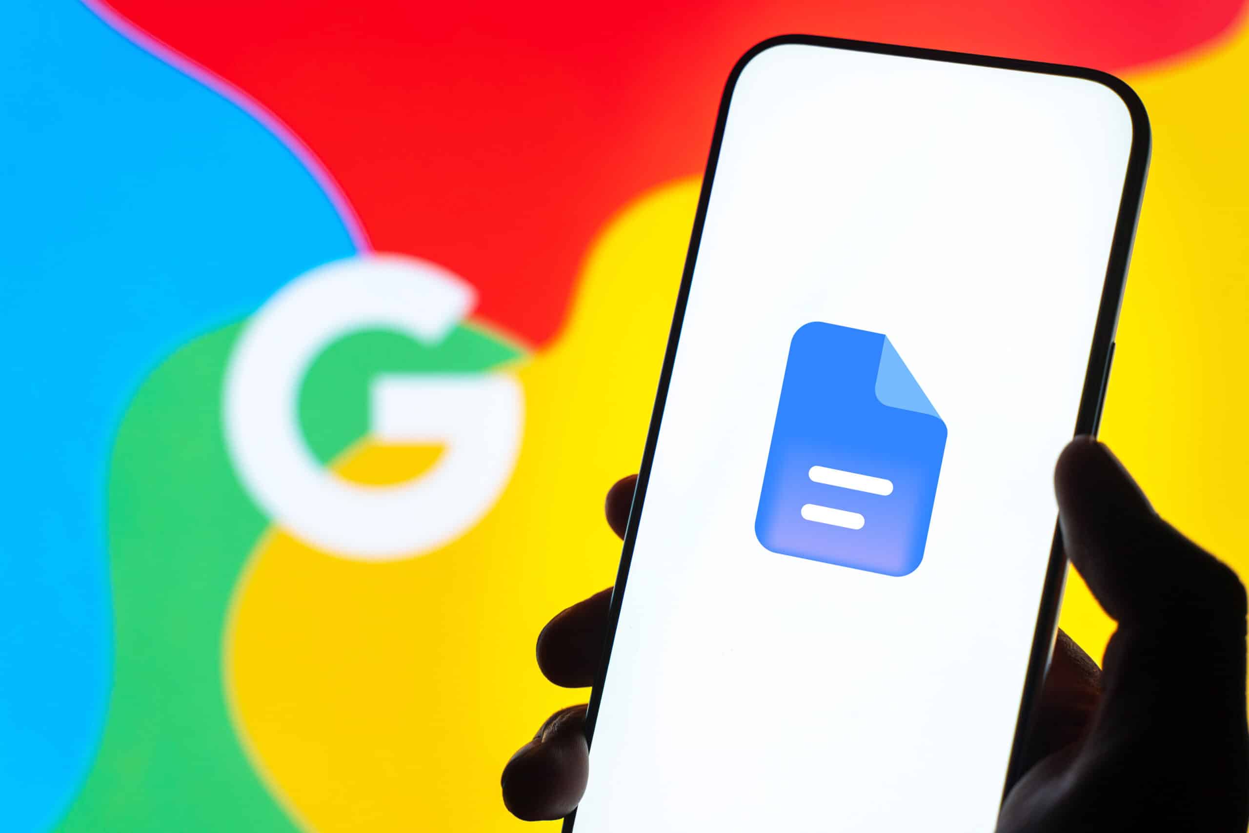 A hand holds a phone showing the Google Docs icon
